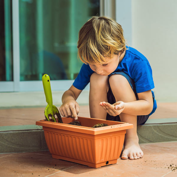 Child planting into Plastic plant trough